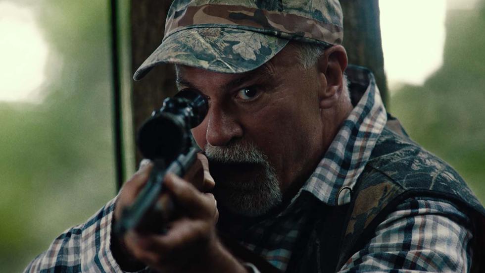 Ten Shots film still man looking through scope of a rifle