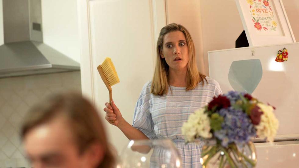 An Ideal Host woman stands with a small broom in her hand.