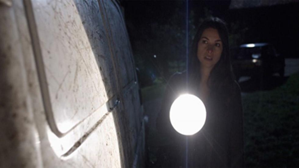 The Other Side woman looks at something with a flashlight
