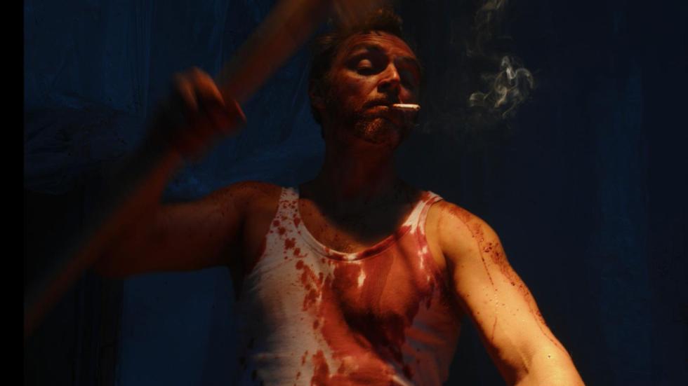 A bloodied man smoking a cigarette while he beats someone