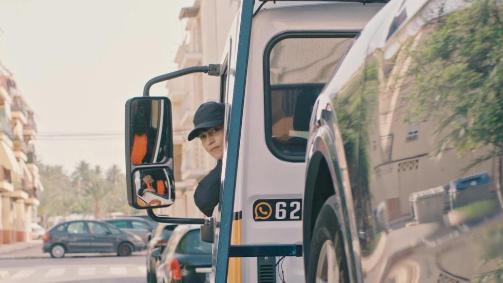 Berta looks back from the driver's seat of her work truck