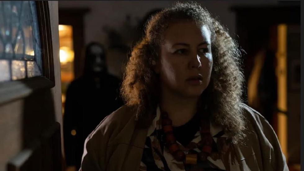 Anne looks worried with a masked man behind her