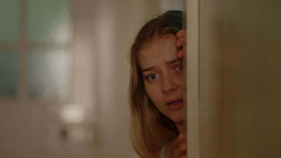 Maya looks from behind a door
