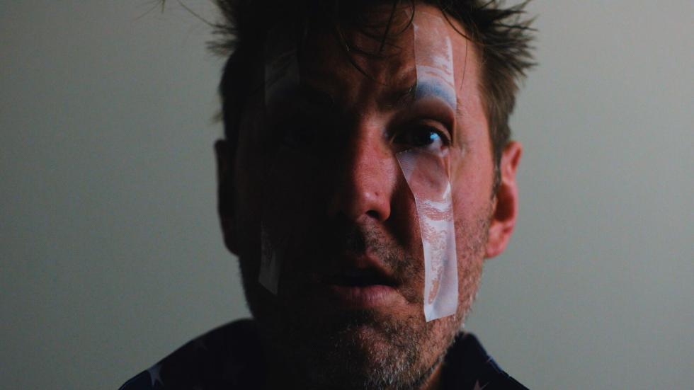 A man with a bandaged wound on his face