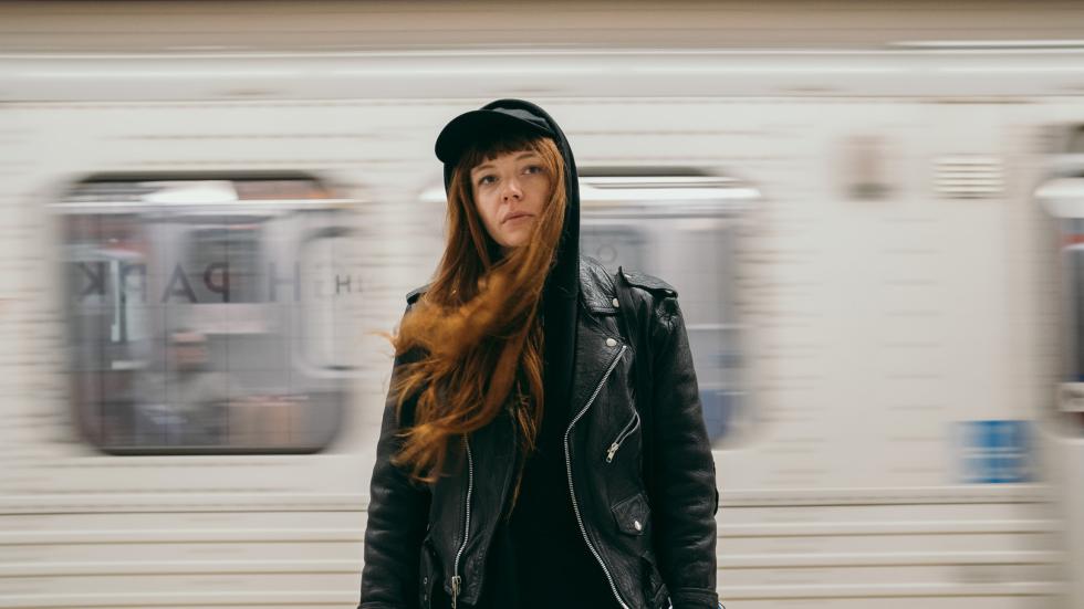 Sid stands in front of a passing subway 