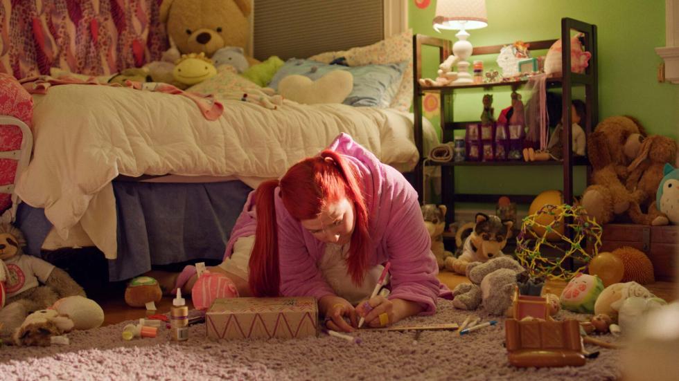 A young woman writes on paper in her bedroom