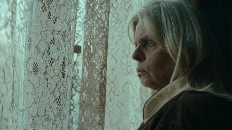 Older woman looks out the window