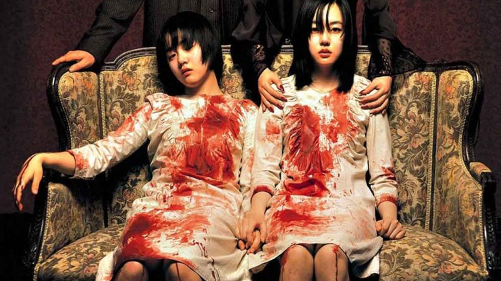 A Tale Of Two Sisters Two sisters in bloody white dresses sit on a couch