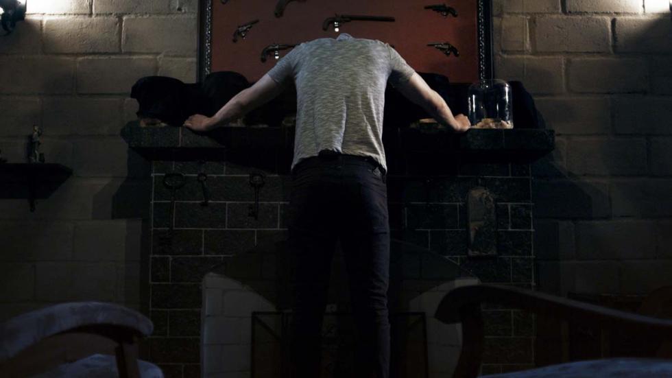 Apostles film still headless man leans against a table