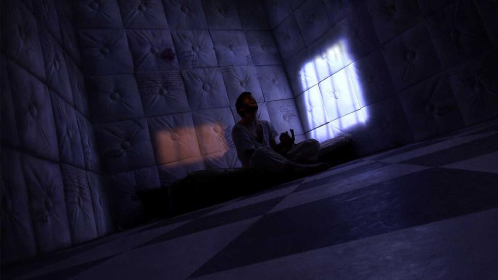 Asylum person sitting in a dark padded room