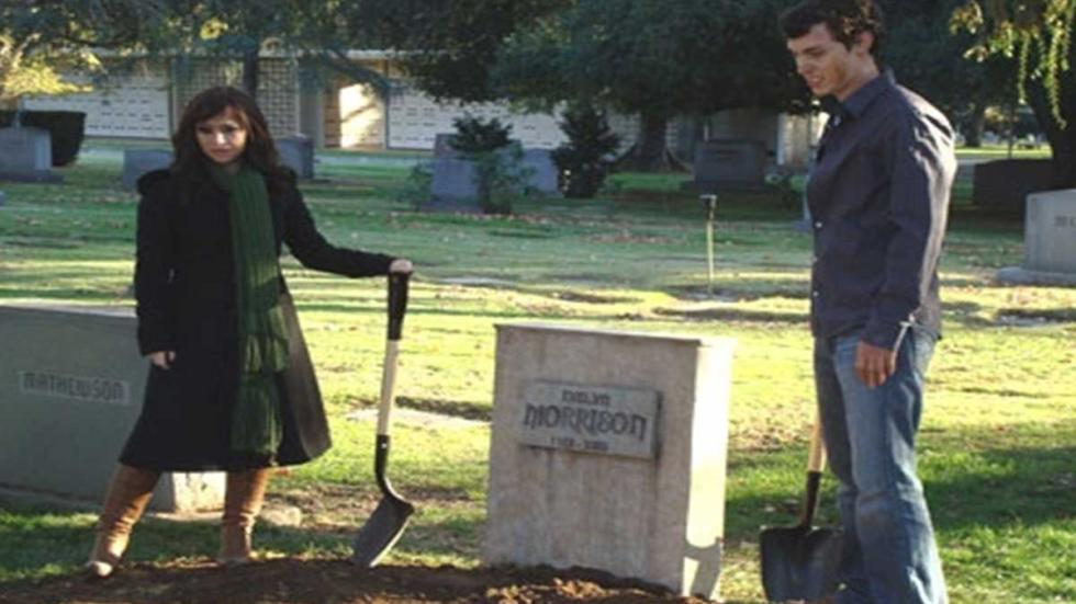Burying The Ex man and woman stand with shovels at a grave
