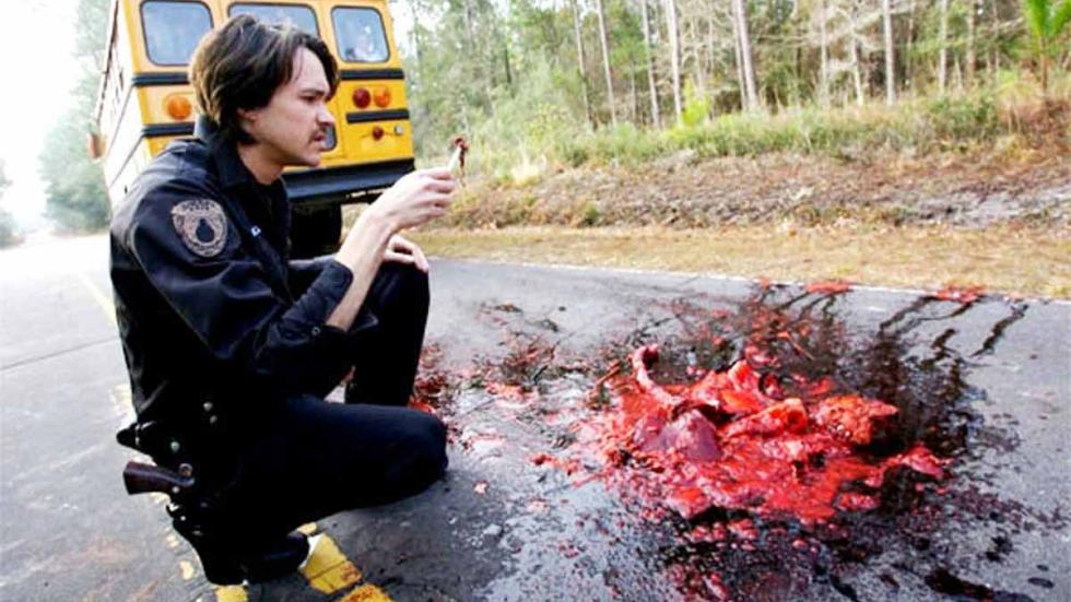Cabin Fever 2: Spring Fever police looks at a piece of road kill on the road