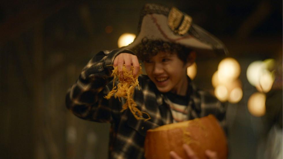 A young boy pulls the insides of the pumpkin out