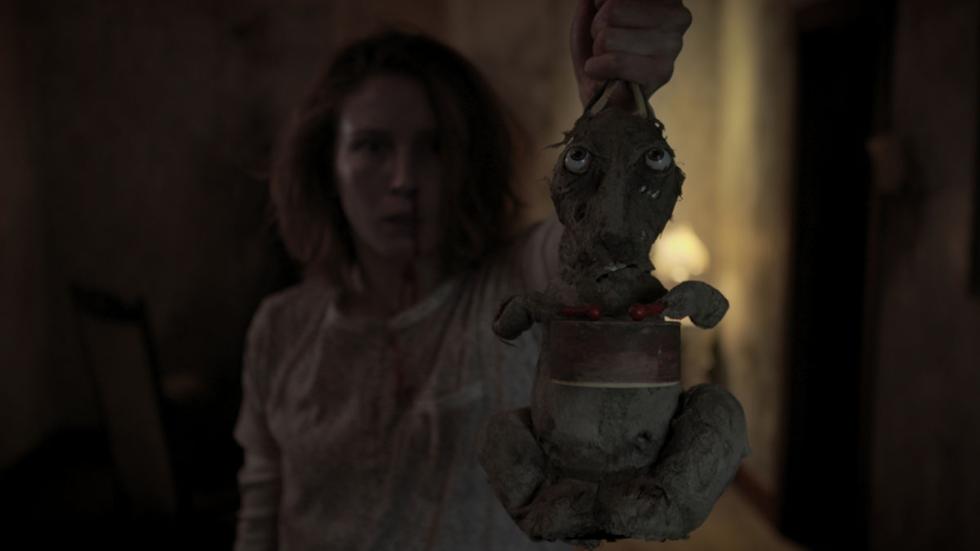 Caveat film still of a Woman holding a scary stuffed animal rabbit
