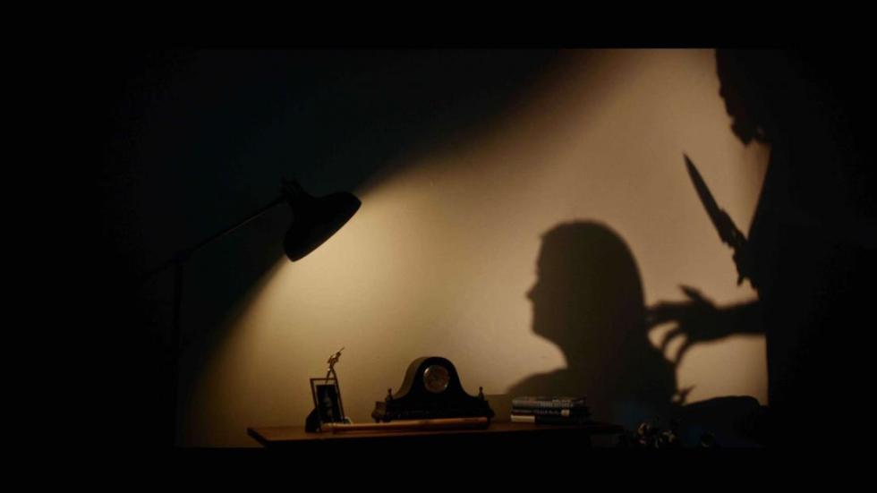 Crockpot film still shadow of knife being held to woman's head.