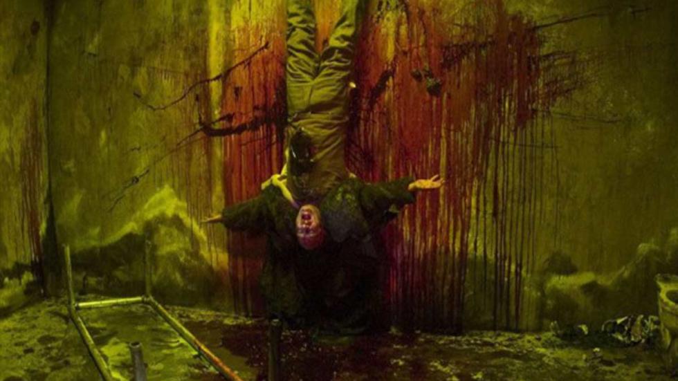 Curandero man hangs upside down against a bloody wall