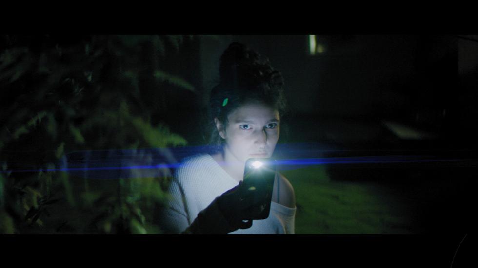 Cut film still woman in the dark shining her cell phone flashlight