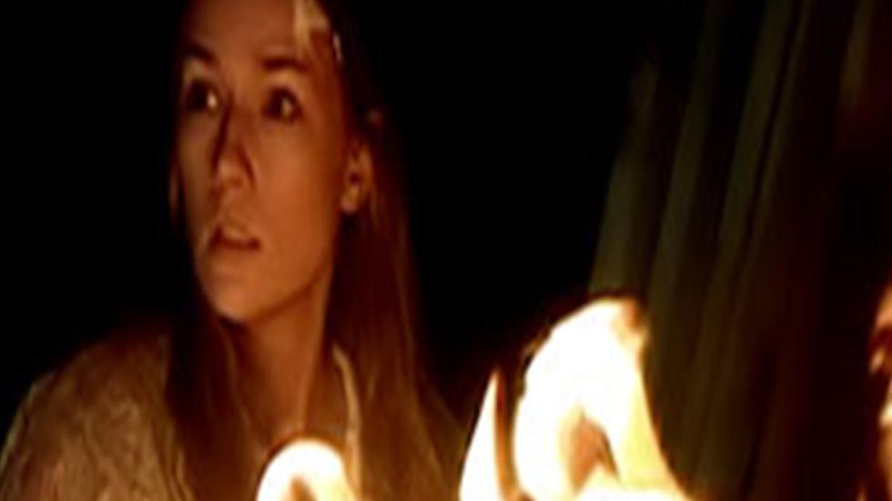 Dead West woman looks off at something near a fire