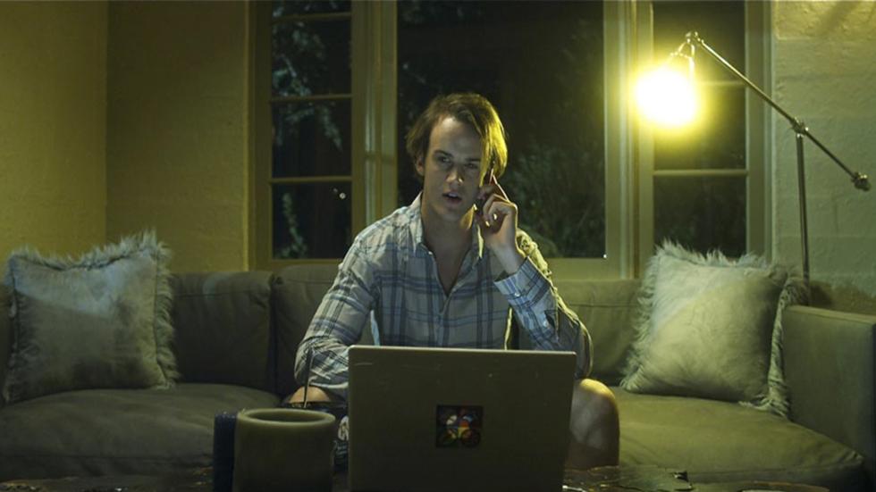 Dembanger A guy talks on the phone and looks at his laptop