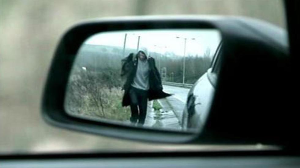Detour man walking  image is seen in a cars sideview mirror