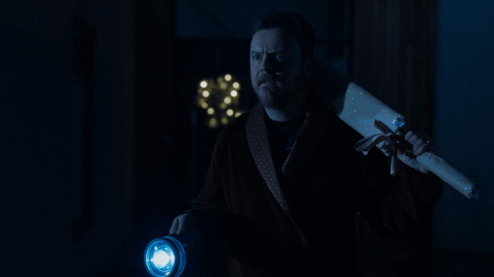 A Man uses a flashlight to search for something outside at night with 