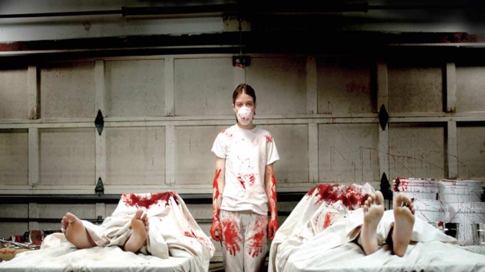 Excision young woman stands between two bloodied bodies