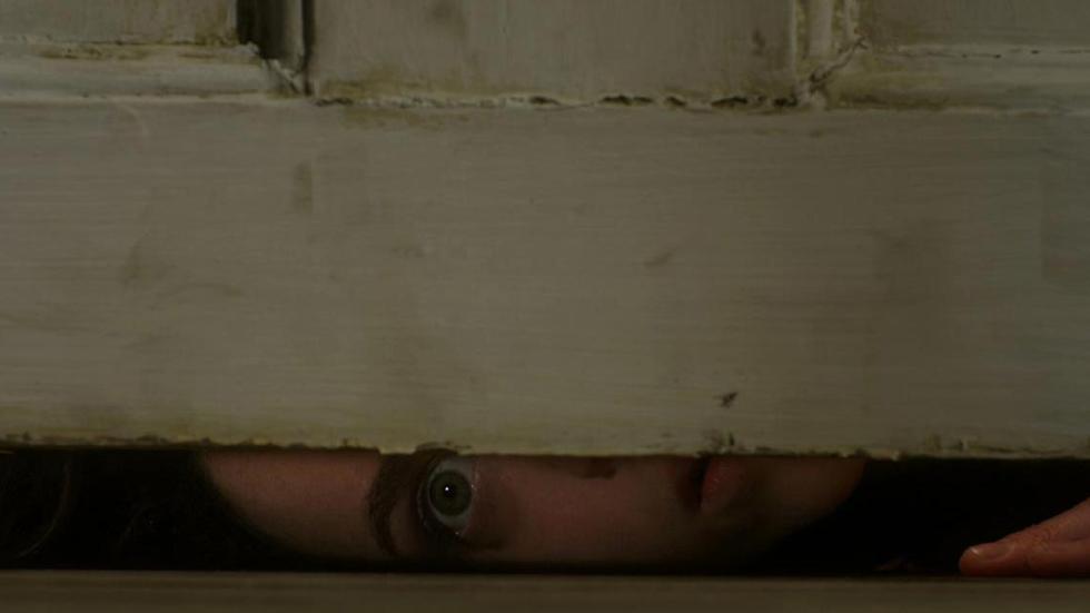 Estranged woman looks from under a door