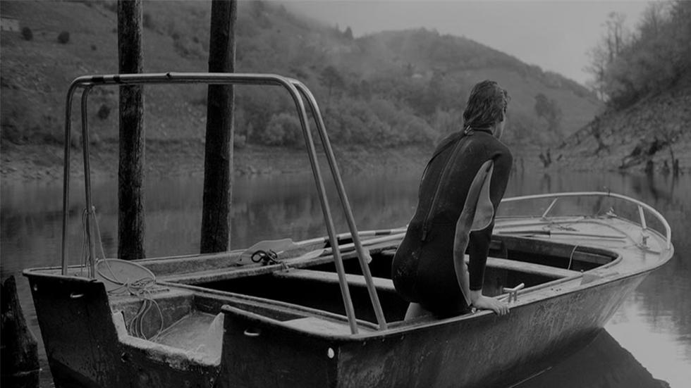 CODA SACRA film still woman on a boat in a calm lake.