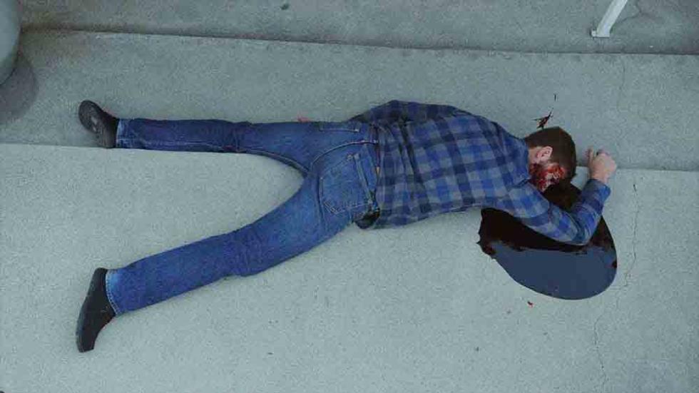 Immortal film still man laying on the ground with pool of blood around his head.