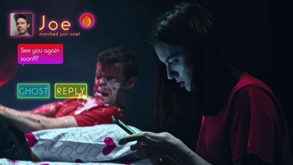 In Your Area film still woman reading her phone with bloody man on bed
