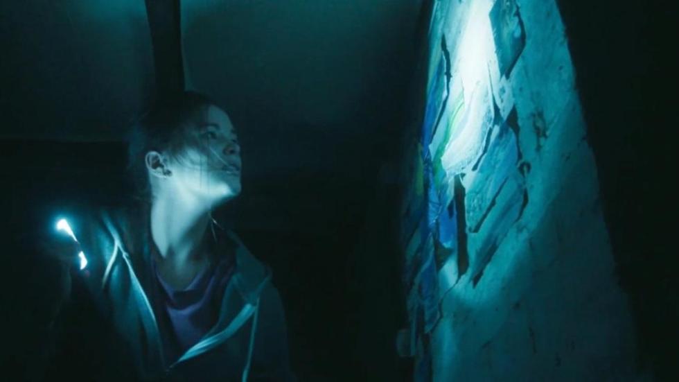 THE HAUNTED film still woman looking at papers on the wall