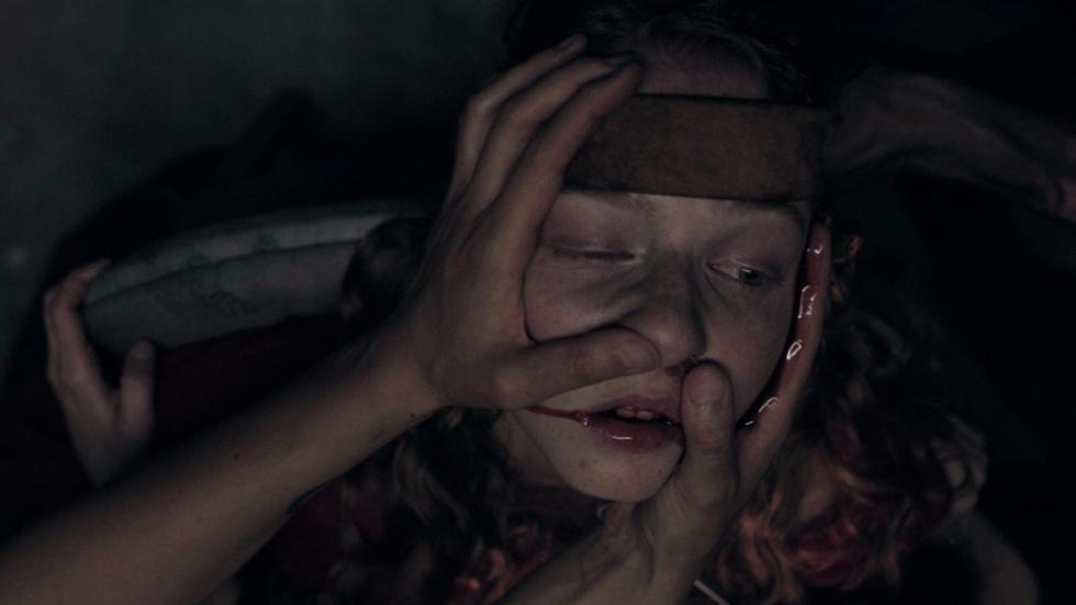 Gavage film still woman being held by her head