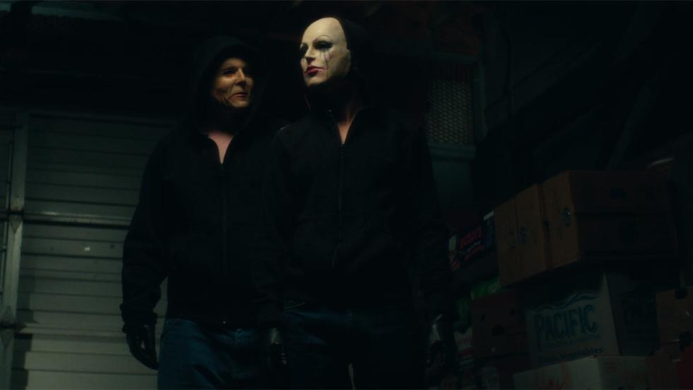 The Girl in the Photographs masked person and man walk
