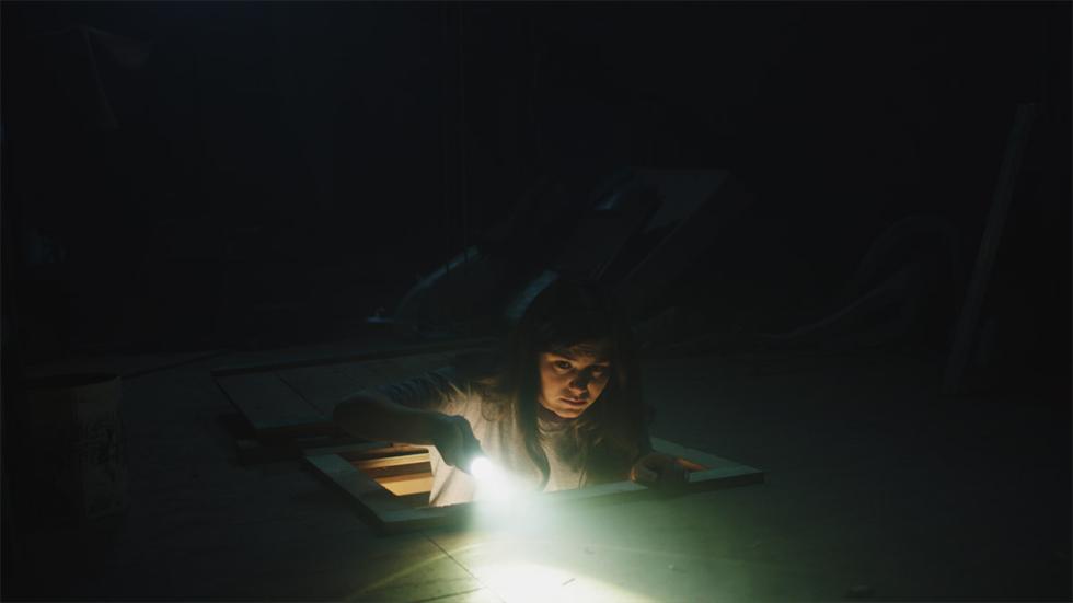The Burden film still woman climbing into the attic with a flashlight
