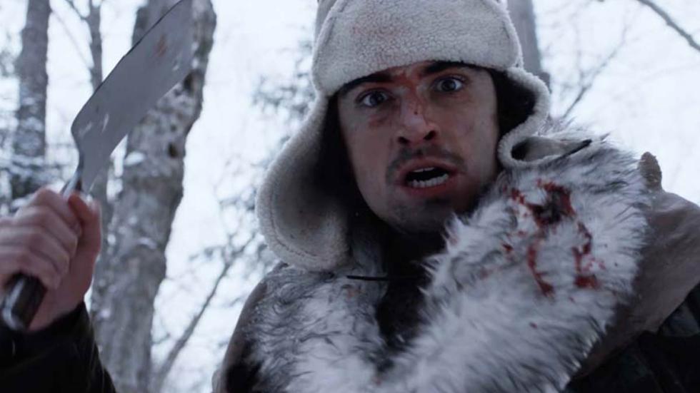 Ice Man film still bloodied man standing with a small shovel in his hand.