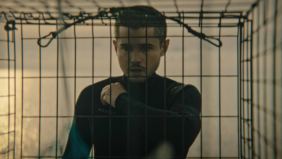Lobsterman in a wetsuit stares at a lobster cage
