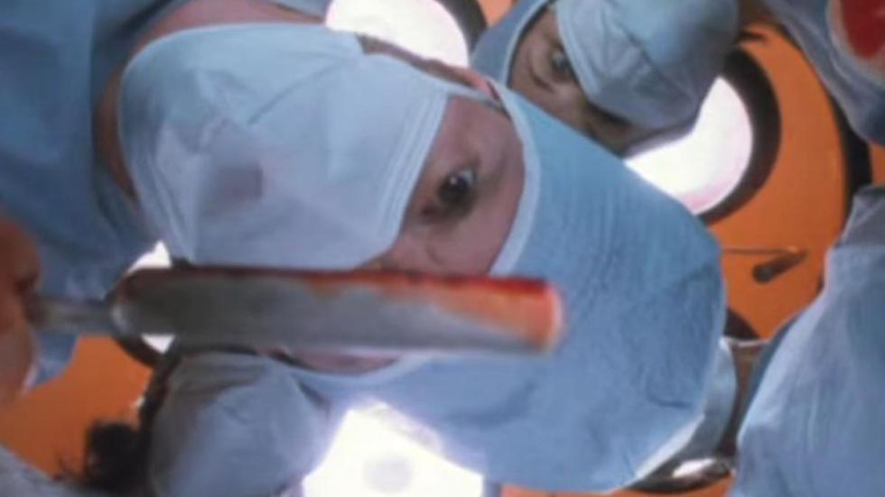 Kolobos doctor with a bloody scalpel leaning over patient