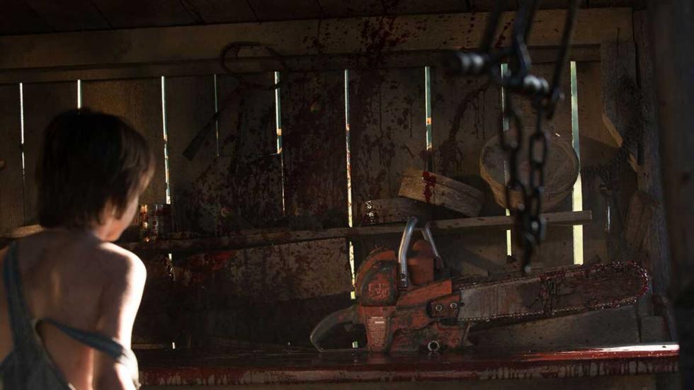Leatherface film still boy looks at torturous tools in a shed.