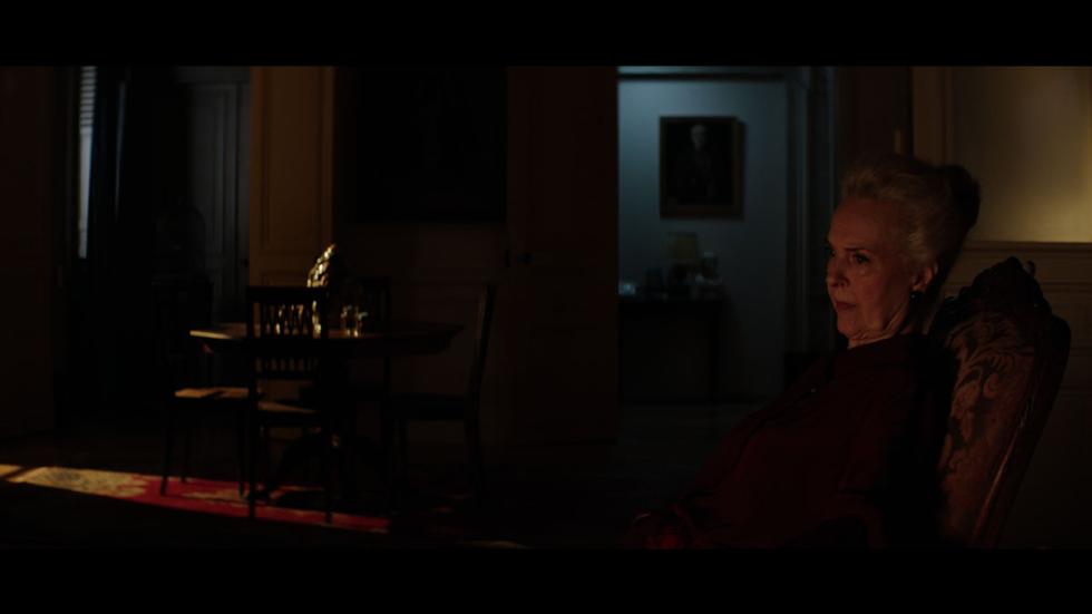 Madame film still woman sitting in a dark room