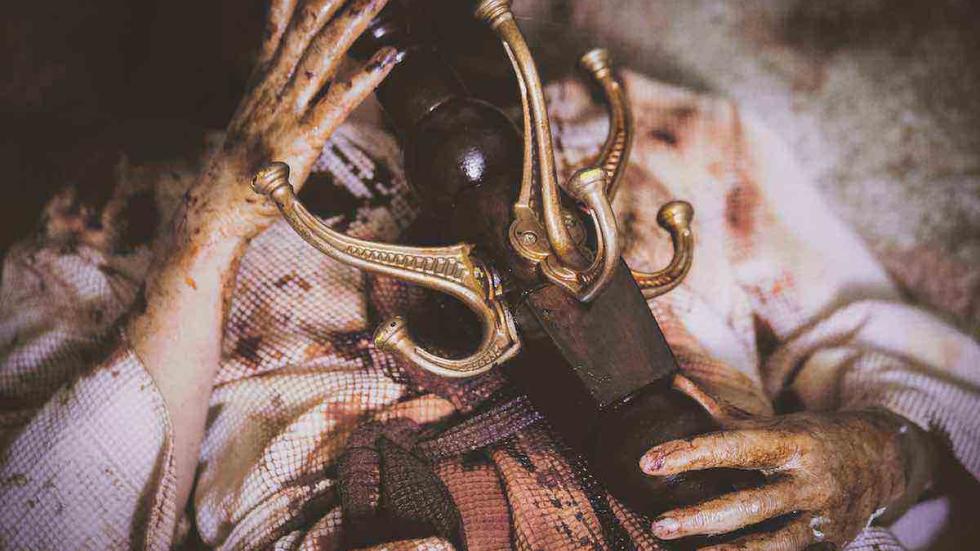 Maggie May film still bloodied woman lays with a coat rack on her