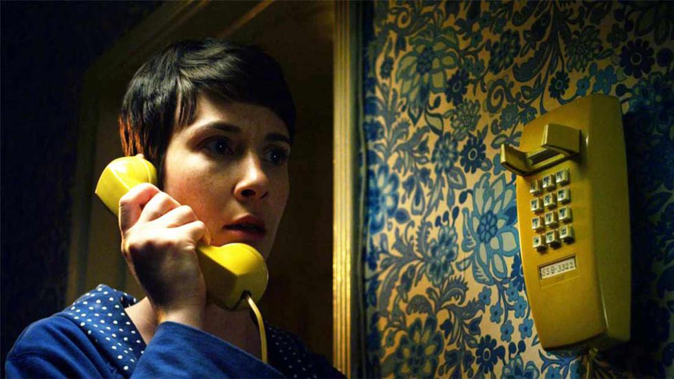 The Night Caller woman talks on a yellow landline phone