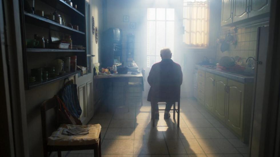 film still old man sitting in chair in the kitchen