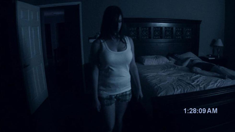 Paranormal Activity woman stands in a dark bedroom