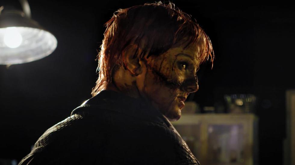 Patchwork disheveled woman covered in dirt looks at something