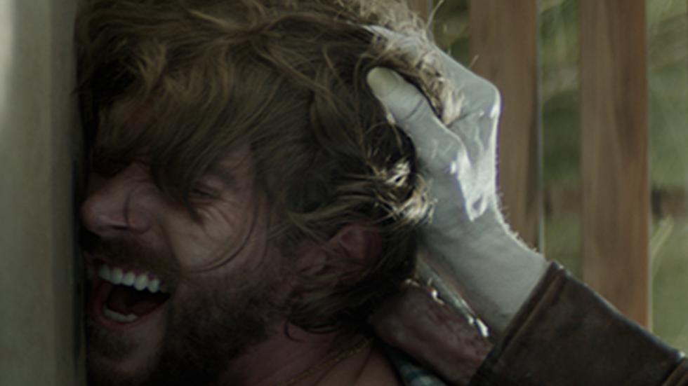 Progeny film still man being held against a wall.