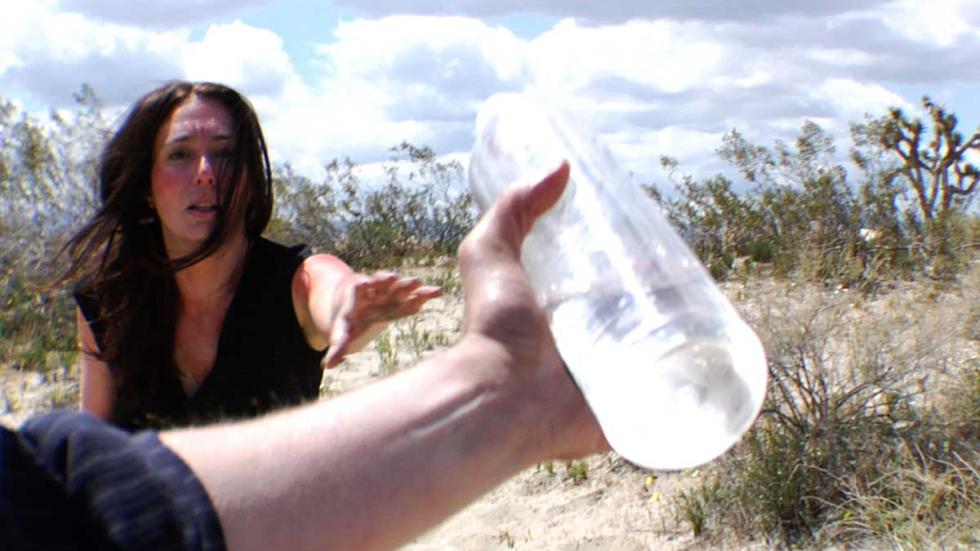 Rations man holds water bottle in front of woman