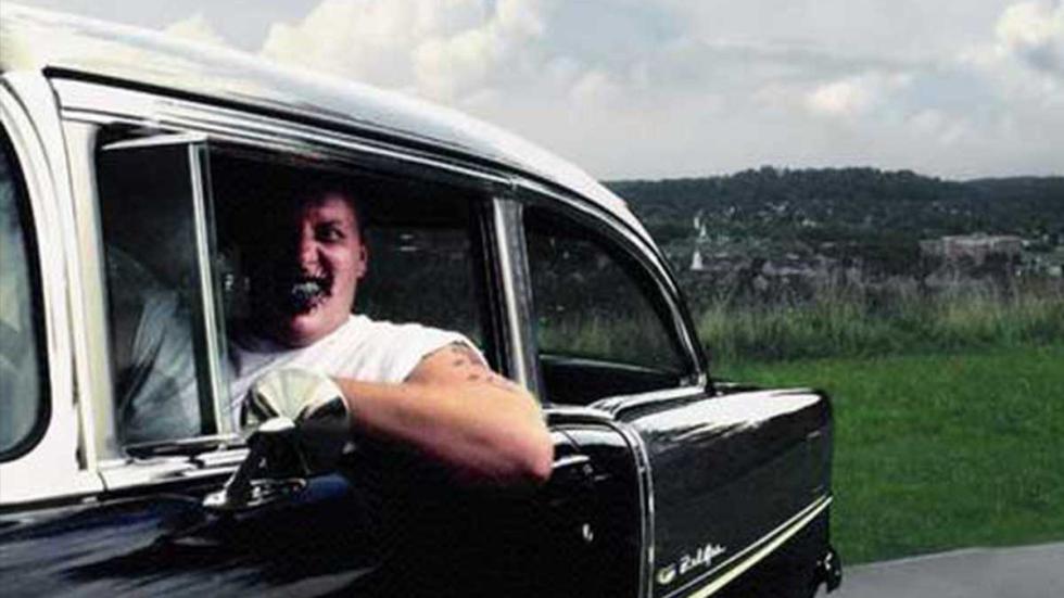 The Road Virus creepy looking man drives a vintage car