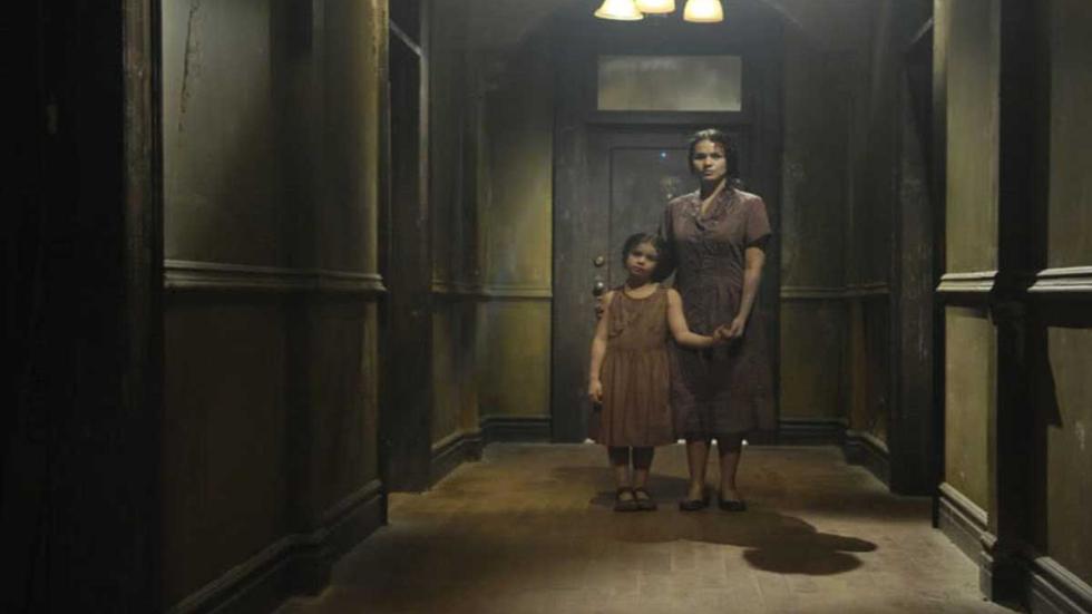 Sigaw (Echo) a woman holds the hand of a child in an apt building hallway