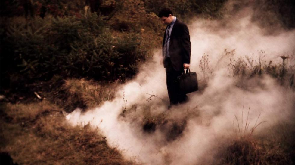 Sinkhole man stands in smoky grass