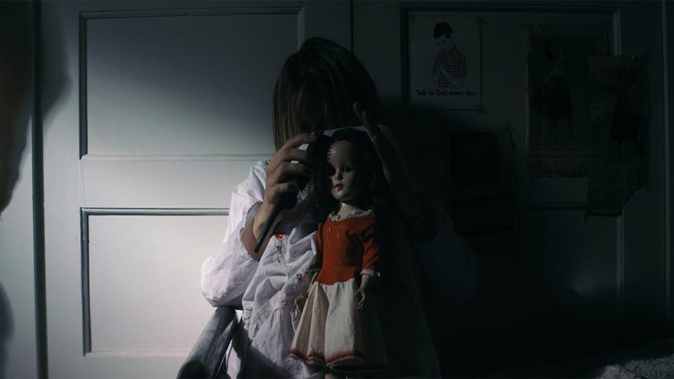 Trash Fire film still young woman sits in the dark with a creepy doll